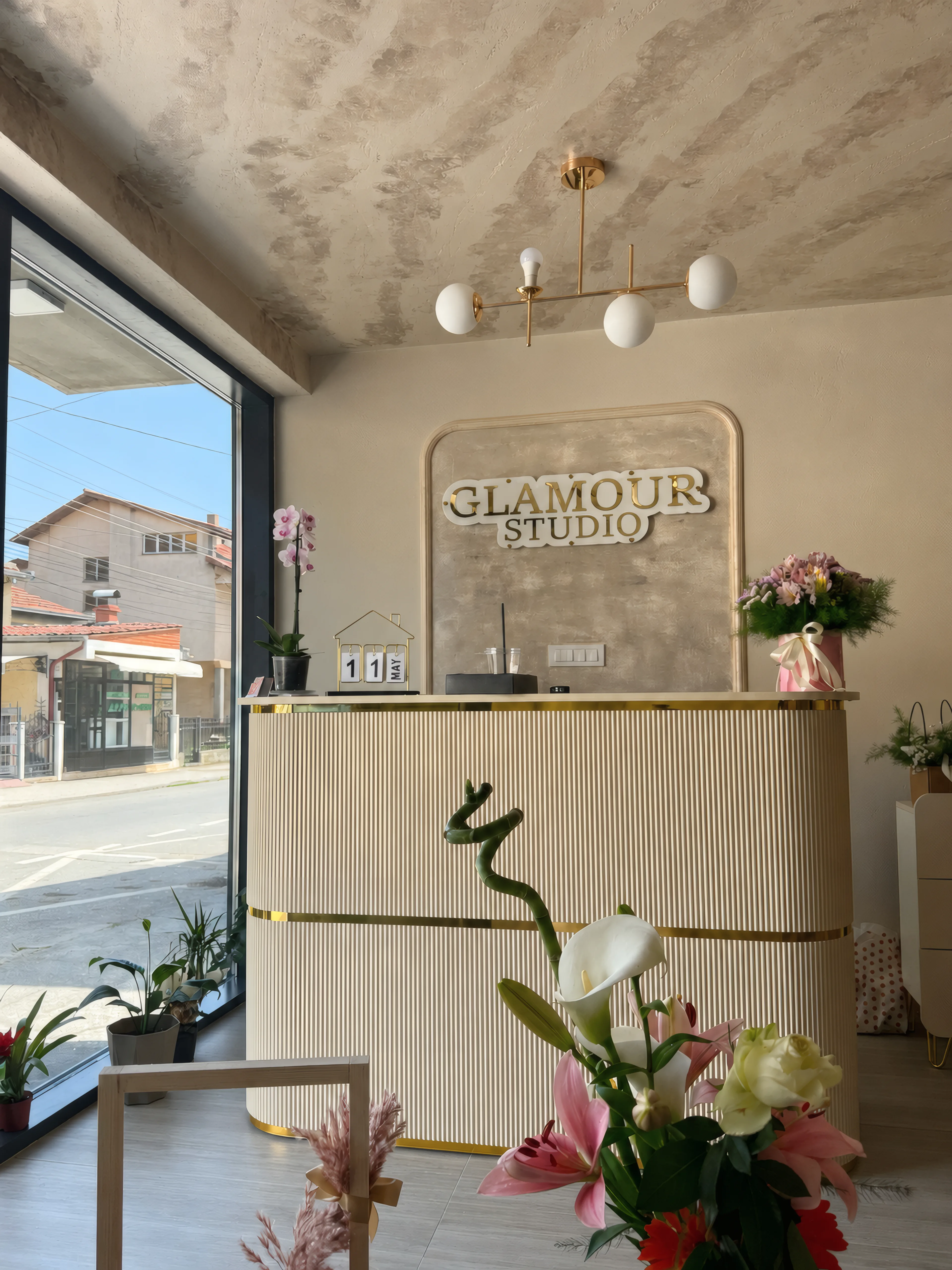 Рецепција со натпис Glamour Studio, цвеќе и прозорец.